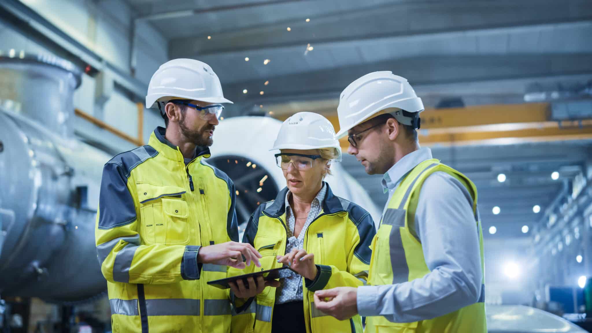 Three Heavy Industry Engineers Stand in Pipe Manufacturing Facto